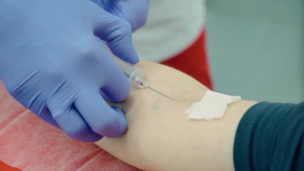 Close-up van het proces waarbij veneus bloed uit de hand van de patiënt in de reageerbuis wordt getrokken met behulp van een injectiespuit met medisch hulpmiddel en naald in het laboratorium van het ziekenhuis of gezondheidscentrum — Stockvideo