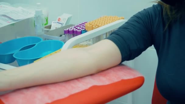 Gloved nurse takes flasks for blood tests in hospital laboratory in front of patient woman in protective face mask — Stock Video