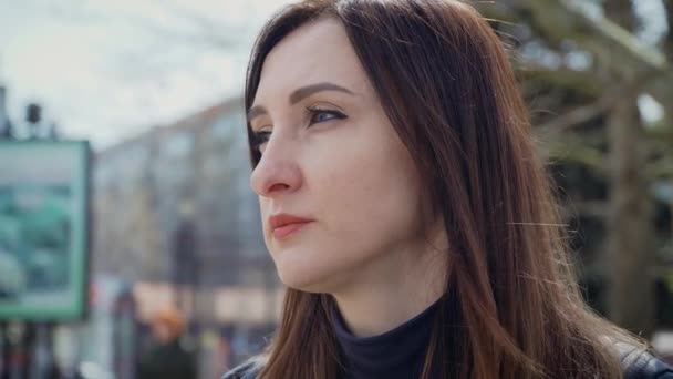 Porträtt av ung kvinna med omtänksam blick står på stadens gata mitt på våren solig dag — Stockvideo