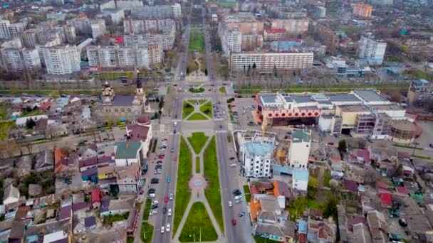 Central street in post Szovjet-európai orosz vagy ukrán város sok mozgó autók és buszok, séta az emberek a járdán, és nyírt gyep zöld fű — Stock videók
