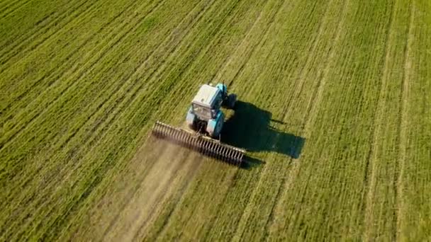 Luchtopname van moderne tractorvoertuigen die op het veld werken en grond verbouwen in landbouwgewassen van tarwe of gerst — Stockvideo