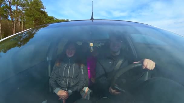 Вид через лобовое стекло движущегося автомобиля на мужчину и женщину со своими детьми по проселочной дороге в сосновом лесу. Страхование гражданской ответственности — стоковое видео