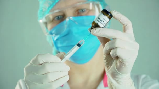 Медичний дослідник у захисній масці для заповнення шприца біотехнологічною вакциною — стокове відео