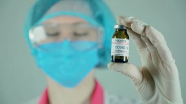 Kadın bilim adamı ampulü elinde tutuyor, yeni ilaçlar geliştiriyor, aşılar yapılıyor.