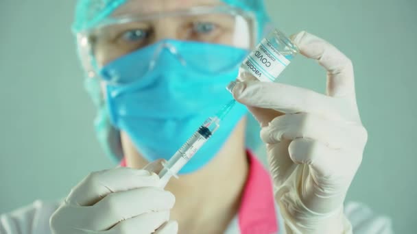 바이오 테크 모디나 백신으로 주사기를 채우고 있는 보호 마스크를 쓰고 있는 의사들 — 비디오