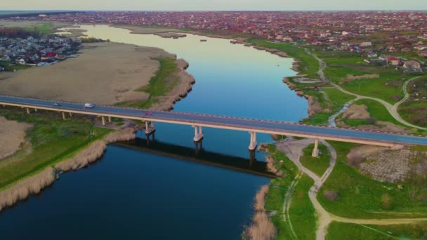 Luchtfoto filmische drone beelden van brug over de rivier in het land gebied met bewegende auto 's en reflectie in diep blauw water in Oekraïne — Stockvideo