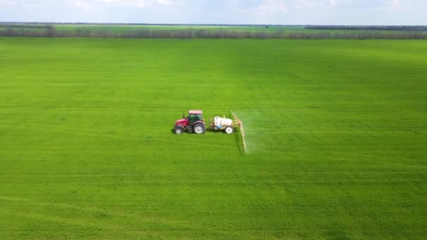 Αεροφωτογραφία του γεωργικού ελκυστήρα ψεκασμού στο χωράφι κριθαριού με ψεκαστήρα, ζιζανιοκτόνα και φυτοφάρμακα. Γεωργικά μηχανήματα εγχέει εντομοκτόνο στο πράσινο πεδίο — Αρχείο Βίντεο