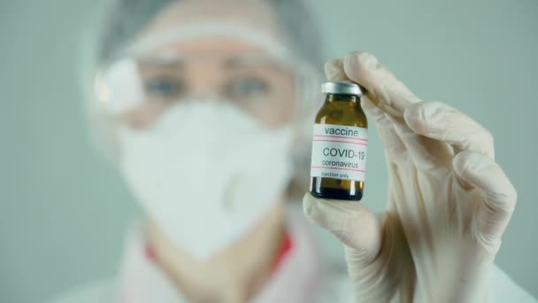 Kadın bilim adamı elinde anti koronavirüs aşısıyla ampul tutuyor. Yeni ilaçlar geliştiriyor. — Stok video