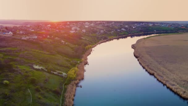 Dron lata nad pięknym zachodem słońca na błękitnej europejskiej rzece pod malowniczą wioską na wzgórzach — Wideo stockowe