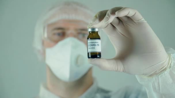 Investigador masculino en desgaste estéril protector sosteniendo tubo médico con muestras de vacuna en laboratorio — Vídeos de Stock