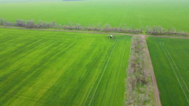 Agricultural farming tractor spraying on field with sprayer, herbicides and pesticides at cloudy spring day — Wideo stockowe