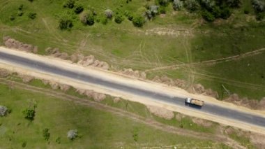 Büyük ve güçlü bir kargo kamyonu, kum dolu bir şekilde yeni asfalt döşenmiş bir şekilde yolda ilerliyor.