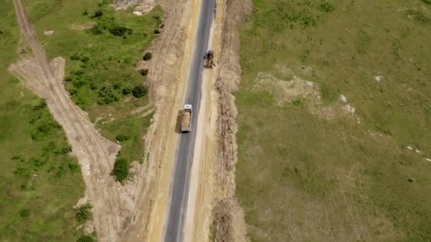 Camion minerario che trasporta sabbia dalla cava alla costruzione di strade e passando vicino al bulldozer pesante. Veduta aerea del lavoro di macchinari minerari e argilla in movimento dalla miniera — Video Stock