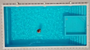 Yüzme havuzunda su sıçratan yetişkin evli bir çift. Yeni evliler balaylarında tropik tatil beldelerinde dinleniyorlar. Erkek ve kadın güneşli bir günde, havuzda serin ve ferahlatıcı suyla öpüşür ve sarılır.