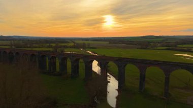 Gün batımında parlayan viyadük hava açısı. Viyadük demiryollarının güzel vadide uçuşan insansız hava aracı görüntüleri. Ünlü yerler, tarihi bölge, doğa manzarasından geçen ulaşım ağı