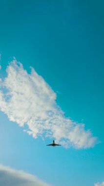 Kanatları geniş ve türbinleri itiş gücü üreten bir jet tepemizde uçuyor. Özel uçak, gövde gölgesi ve iniş takımları dikey doğrultuda açık havada hareket ediyor. İş jeti motorlu bulutların üzerinde uçuyor