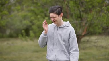 Genç bir çocuk, boğucu kokudan burnu burnu buruşmuş ve öksürüyor. Genç adam burnunu koruyor, ürküyor ve güçlü kokuya tepki veriyor. Ergenlik çağındaki çocuk burnunu tutuyor, ağır bir koku yüzünden rahatsız ve öksürüyor.