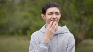 Neşeli genç çocuk çenesini parmaklarıyla kaşıyordu. Neşeli ergenler çenelerine dokunup düşünceli davranıyorlar. Mutlu genç adam nazikçe çenesini parmaklarıyla ovalıyor.