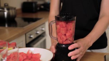 Karıştırmaya hazır karpuz küpleriyle dolu bir blender. Kavanozun içine sıkıca doldurulmuş taze kırmızı meyve. Meyve suyunu ferahlatıcı içeceğe hazırlıyorum. Mutfak sahnesi harmanlanmadan önce olgun kavun gösteriyor