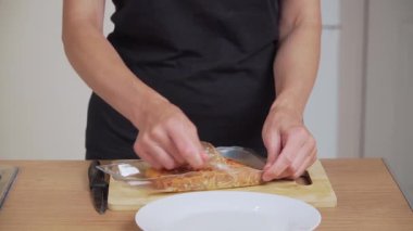 Plastik paketten tütsülenmiş balık açıyorum. Gemide deneyimli fileto hazırlayan tanınmamış kişi. Şeffaf ambalajdan tütsülenmiş somon alıyorum. Suşi için füme balık hazırlıyorum.