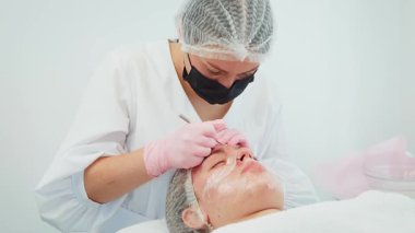 Güzellik uzmanı nazikçe ve ustalıkla cilt kirliliğini gidererek ten rengini arttırıyor. Profesyonel teknikler uygulayan kadın yüz tedavisine odaklanıyor. Işıl ışıl bir ten elde etmek için titiz bir tedavi gören kız.