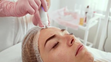 Dermatoloji ofisinde ileri düzey bir aletle hidroterapi tedavisi gören hasta kadın. Güzellik uzmanı derin deri dökülmesi ve su kaybı için hassas ekipmanlarla cilt üzerinde dikkatlice çalışıyor.