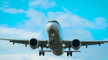 İniş takımlarıyla alçaktan uçan uçaklar bulutlarla aydınlık gökyüzünün altına kadar uzanıyor. Mavi gökyüzüne doğru tekerlekleri inen bir jet uçağı piste yaklaşıyor. Yolcu uçağı geniş iniş takımlarıyla dağınık bulutların arasından iniyor.