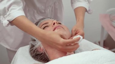 Profesyonel kozmetoloji kliniğinde kadın yüzünden ürün çıkarma prosedürü. Uzman kadın derisi temizleme uzmanı tarafından yapılan tedavi. Profesyonel cilt bakımı için kadın yüzünde güzellik terapisti tarafından yapılan dikkatli temizlik.