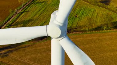 Dönen rüzgar türbinleri rüzgar çiftliğinde yeşil yenilenebilir enerji üretiyor. Rüzgar türbini yenilenebilir enerji üretmek için geniş bıçakları hareket ettiriyor. Hareket eden pervaneler rüzgar çiftliğinde yenilenebilir enerji üretiyor