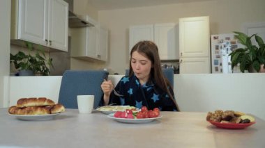 Mutfakta oturan kız patatesli hamur köftesi yiyor. Çocuk evde patates köftesi tabağıyla yemek yiyor. Masadaki genç, geleneksel köfteleri patates dolgulu yiyor.