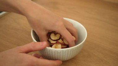 Sağlıklı yemek için ev yapımı elmaları kaseye karıştırıyorum. Besleyici gıdaları teşvik etmek için karıştırılmış elma dilimleri. Sağlıklı beslenmeyi destekleyen doğal kurutulmuş meyveyi kabın içine atmak