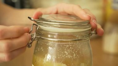 Tanınmayan biri tarafından balla kavanozu açıp kapamak. İçinde bal olan konteynır açık bir kapalı eylem gerçekleştiriyor. Bal ile çalışan cam kap tekrarlanan kapak hareketi yapıyor