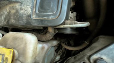 Kirli çalışan motor çevirici alternatör ve AC sürücü kemeri. Kirli motor, aksesuar ve makara sistemi ile çalışıyor. Tozlu güç ünitesi jeneratör kayışı ve klima kayışıyla çalışıyor.