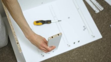 Şifoniyer montajı sırasında çekmecenin yan kısmını inceliyorum. Tamirci, DIY kabin inşaatını hazırlarken mobilya tahtasını inceliyor. Ahşap işçilerinin marangozluk projesi sırasında panelin hizalanmasını denetlemesi