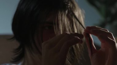 Zihinsel hastalık, genç bir adamın endişeli bir odak noktasında saçlarını kıvırmasına neden olur. Loş odada izole edilmiş bir kişi duygusal gerilim ve iç mücadele belirtileri gösteriyor. Gençlerin saçlarıyla oynaşması derin psikolojik yorgunluk ve...