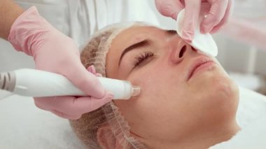 Güzellik uzmanı kadın estetik merkezinde elektrikli süpürge kullanıyor. Profesyonel cilt bakımı gören hasta. Aygıt kirliliği temizlemeye ve deri dokusunu geliştirmeye yardımcı olur