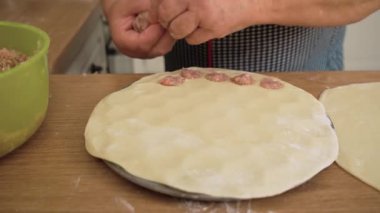 Eti rulo hamura dolduruyorum. Kıyma dilimleri düzenleyen tanınmayan biri. Hamur kağıtlarını küçük kepçelerle dolduruyorum. Pelmeni kıyma ile hazırlanıyor.