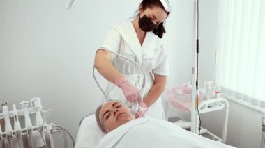 Güzellik uzmanı kozmetik dermatoloji kliniğinde Oksijen Enfüzyon Yüz Makinesi kullanıyor. Dişi, klinikte gelişmiş ekipmanlarla cilt bakımı yapıyor. Dermatoloji ortamında Oksijen Enfüzyon Yüz Makinesi ile kadın yürütme prosedürü