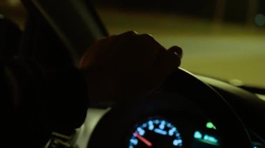 Geceleri tanınmayan bir adam otobanda araba kullanırken direksiyonda el dinlenmesi. Erkek seyir yolu, sokak ışıklarının altında sürükleyici tekerlek. Otoyol boyunca gece sürüşü, yanan otoyolda direksiyon sallama.