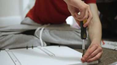 Şifoniyer montajı sırasında çekmeceye raptiye sıkıştırılıyor. DIY kabinesi hazırlarken mobilya tahtasının üzerinde toplanma öğesi perhizleniyor. Çekmece inşaatı sırasında marangozluk projesinde donanım bileşeni sağlanıyor