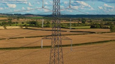 Tarım arazisinde duran kule kırsal kesimden elektrik iletiyor. Yüksek voltajlı çelik güç pilleri elektrik iletiyor. Elektrik enerjisi taşıyan tarım arazisinde yükselen direkler