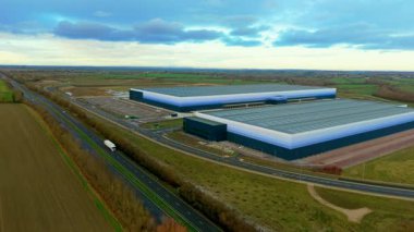 Kargo kamyonu, sanayi lojistiğini destekleyen depo tesislerinin yanındaki otoyol boyunca mal taşıyor. Nakliye aracı dağıtım merkezleri arasında ürünleri taşıyor tedarik dolaşımını ve ticari akışı sağlıyor. Endüstriyel altyapı