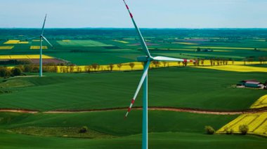 Rüzgar jeneratörleri renkli tarım arazileri üzerinde yenilenebilir elektrik üretiyor. Rüzgâr türbinleri temiz enerji üreterek dönen bıçaklar üretiyor. Yel değirmenleri yeşil arazinin üzerinde dönerken sürdürülebilir enerji üretiyor