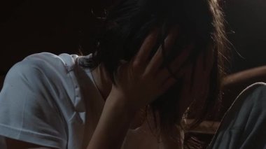 Acı, pişmanlık ve depresyon derin duygusal mücadelenin içinde başını tutan genç adamı bunaltıyor. Öne doğru eğilen kişi iç gerilim ve sessiz umutsuzluk belirtileri gösteriyor. Yüzü kaplayan ergen, ağır psikolojik stres ve umutsuz yorgunluğu yansıtıyor.