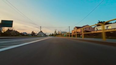 Sıcak Işık ve Uzak Ağaçlarla Sunset 'te Asfalt Yolu boyunca sürmek Huzurlu Atmosfer Oluşturur, nefes kesici POV görünümü. Sıcak altın ışıkla asfalt yolda gün batımında gölgeler düşüyor, huzur ve özgürlük hissi uyandırıyor.