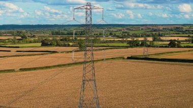 Altın tarım arazisinde ayakta duran direkler elektrik enerjisi yayıyor. Elektrik, yüksek gerilim kablolarından iletiliyor. Tarımsal alanların üzerinde yükselen kule kırsal alanda güç taşıyor.