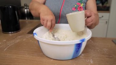 Kadehten klozete un dökerek. Tanımlanamayan kişi karışıma sıvı ekliyor. Malzemeyi kaşıkla karıştırıyorum. Ev yapımı ekmek için hamur hazırlıyorum.