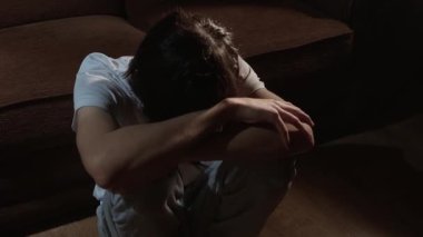 Karanlık odada yerde oturan yalnız bir adam umutsuzluk ve depresyon hissediyor. Yere kıvrılmış biri duygusal çöküntü ve ezici bir üzüntü yaşıyor. Genç adam kollarının üzerinde dinleniyor. Derin umutsuzluk ve zihinsel yorgunluk gösteriyor.