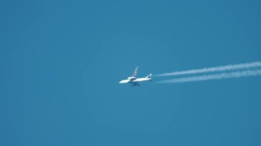 Yüksek irtifada mavi gökyüzünde uçan bir jet uçağı. Uçak kimyasal izler bırakıyor beyaz zıtlıklar oluşturuyor, atmosferi kirletiyor. Küresel çapta zararlı emisyonlar yayan ticari uçak, iklim değişikliğini etkiliyor