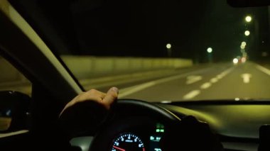 Tanımlanamayan bir adam sokak lambalarının altında boş otoyolda araba kullanırken eller direksiyonda dinleniyor. Erkek seyir yolu, direksiyon açık direklerle karanlık şeritte. Gece otobanında sürmek, parlayan lambaların altında direksiyon sallamak